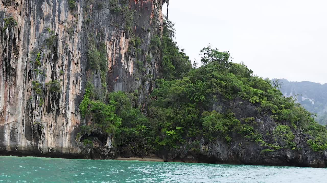 barco pasando por acantilados exuberantes y mar turquesa