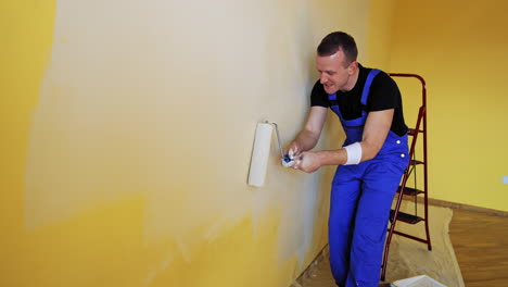 new style renovation. workman in the uniforms painting the walls with paint roller in a house. construction roller painting walls.