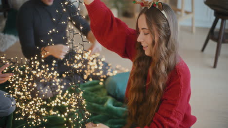 mujer clasificando luces brillantes enredadas con amigos