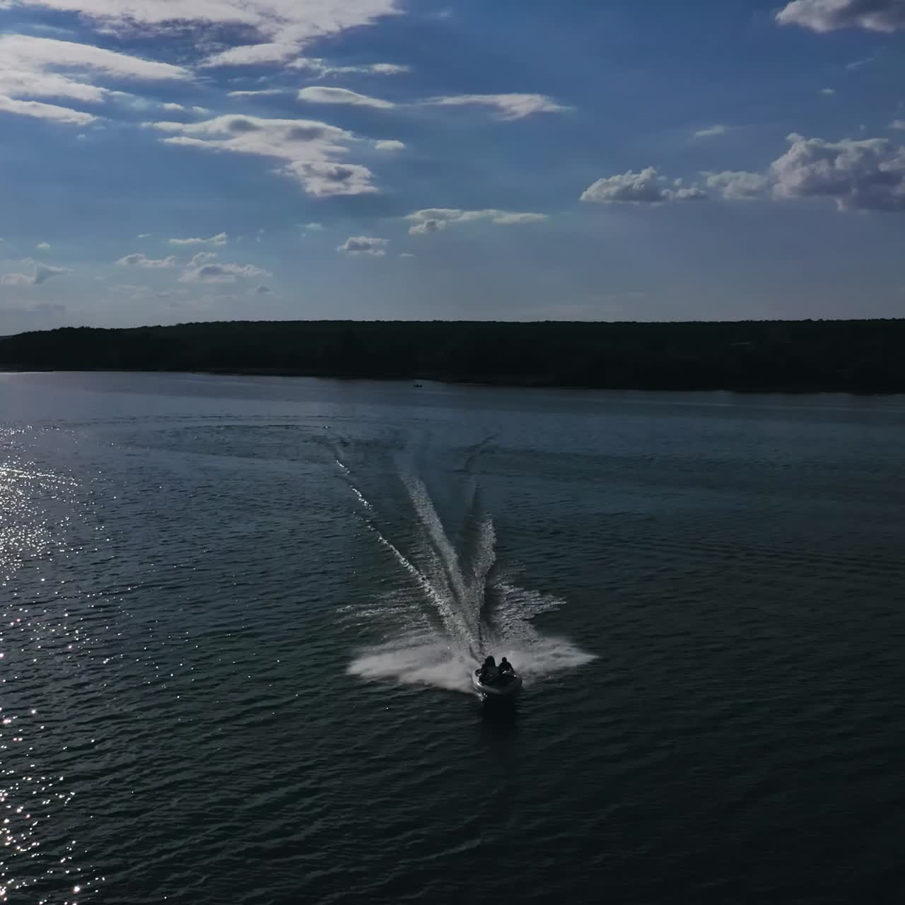 Motor boat moves on water. Amazing view on a river and boat floating at beautiful silver path on water from the setting sun. Aerial view.