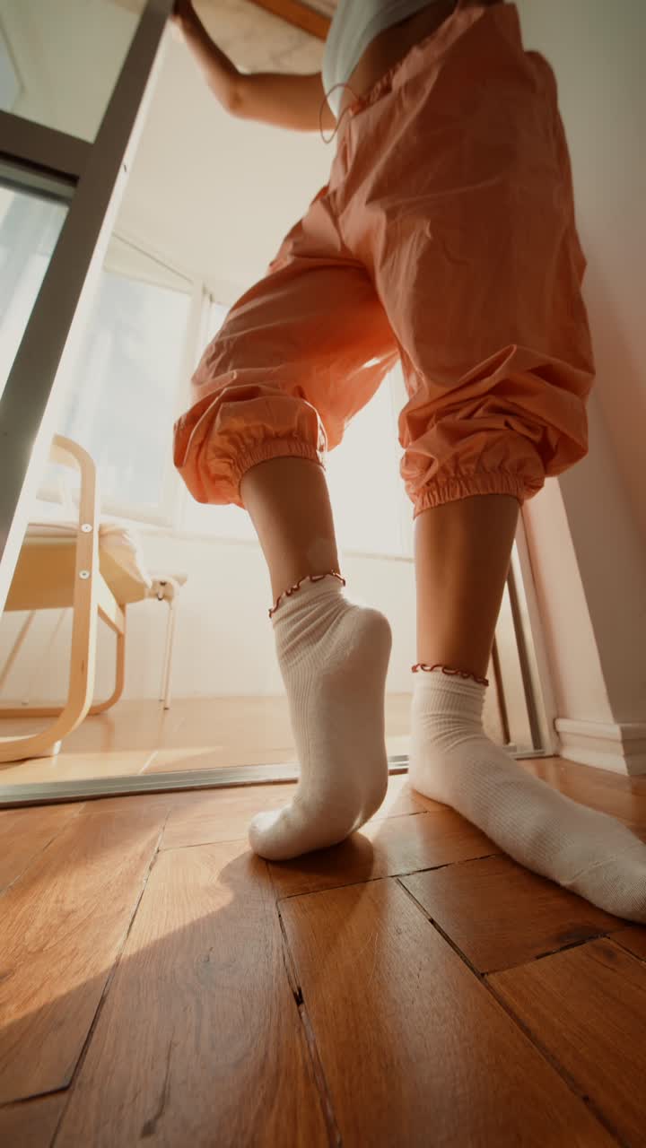 A woman in socks and trousers inside a bedroom