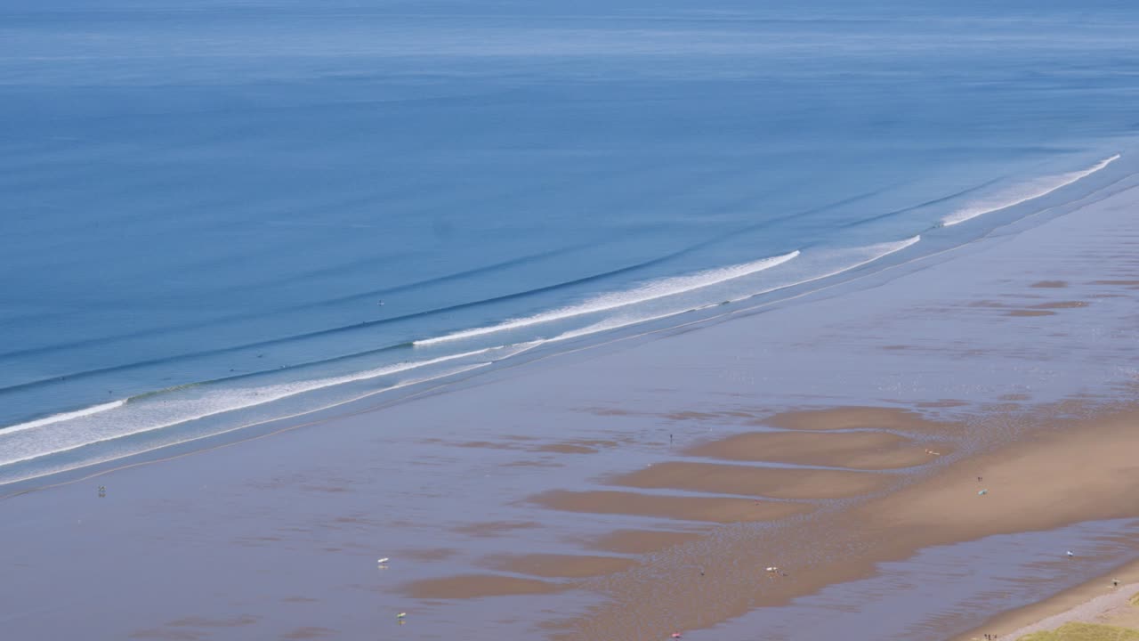 Aerial View of a Sandy Beach with Waves and People