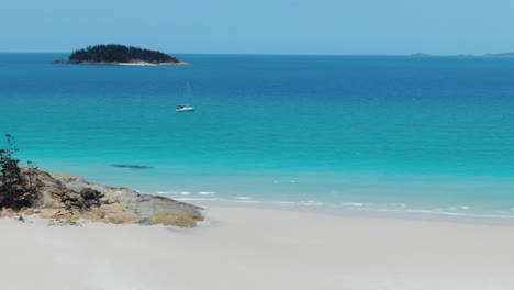 Volando-Increíble-Playa-De-Arena-Blanca-Acercándose-A-Un-Velero-Blanco-Amarrado-Justo-Al-Lado-De-La-Costa,-Antena-De-Drones,-Qld-Australia