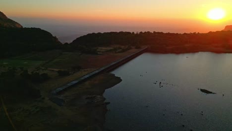 Vista-Aérea-Del-Atardecer-Dorado-Sobre-La-Presa-Ghatghar-Y-Kokan-Kada-Bhandardhara-Rodeado-De-Algunas-Colinas-Increíbles-Maharashtra-India-4k-Drone