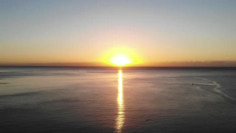 golden yellow morning sunrise on horizon of english channel with bird flying underneath. aerial rising