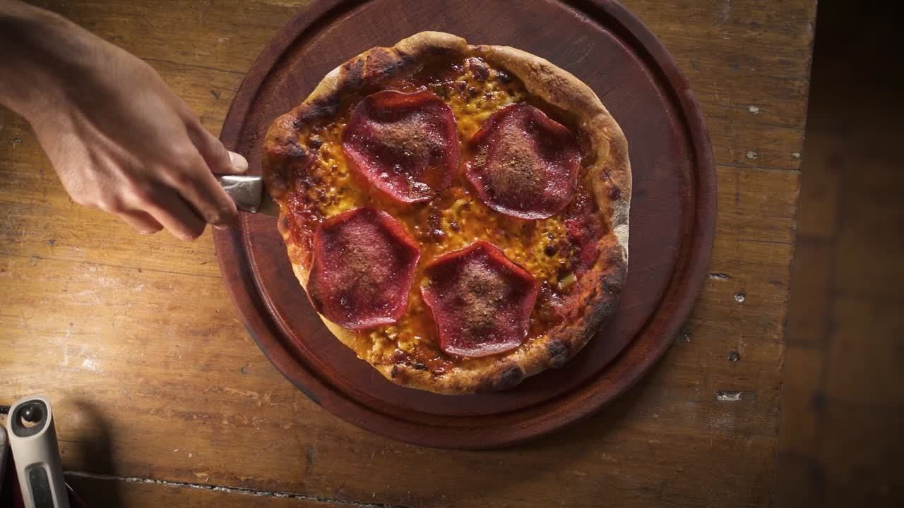 condimento con aceite de oliva ahumado caliente deliciosa pizza de pepperoni casera en la vista superior de la mesa de madera cámara lenta 60fps