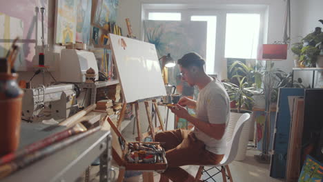 male artist using palette knife while creating painting