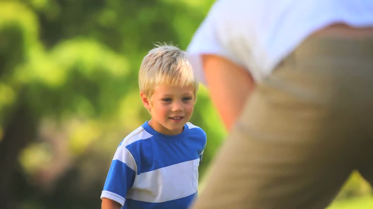 어린 소년 이 아버지 와 함께 공 을 치고 있다