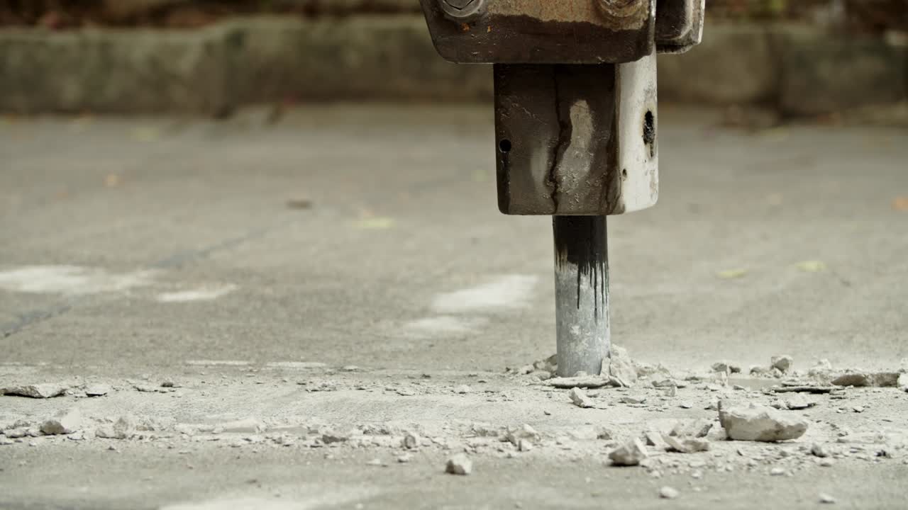 Close-up of excavator hydraulic arm rock breaker working on concrete road