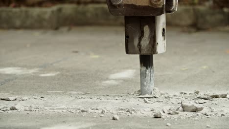 close-up of excavator hydraulic arm rock breaker working on concrete road