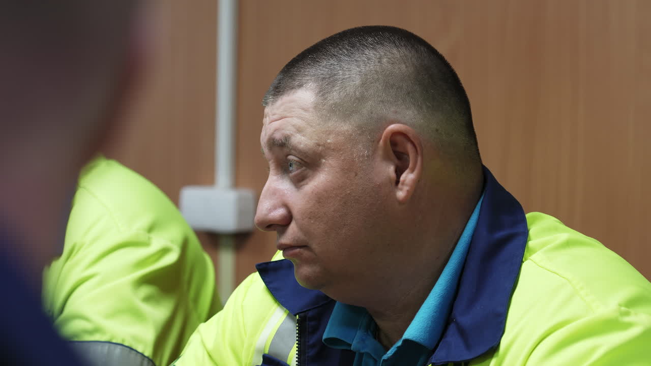 A man in a high-visibility uniform in profile