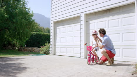 father teaching daughter how to ride a bicycle