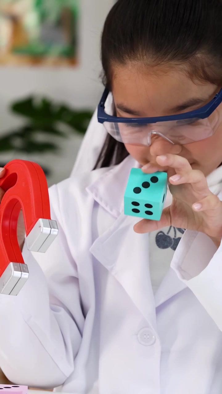Siswa muda mengenakan jas lab menjelajahi magnetisme dan pembesaran selama pelajaran sains di kelas