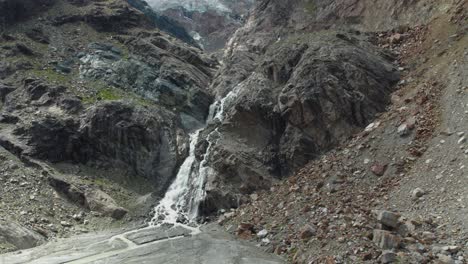 Luftflug-Auf-Eine-Massive-Bergformation-Mit-Wildem-Wasserfall-Und-Fluss,-Atemberaubende-Drohnenaufnahme-über-Den-Schweizer-Alpen-In-Saas-Fee