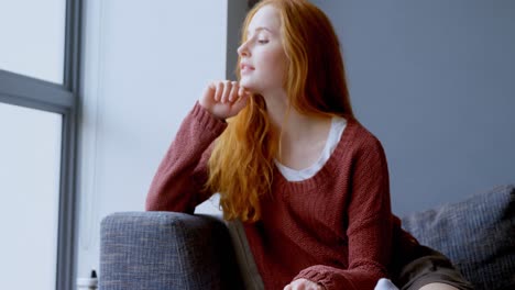 Woman-looking-through-window-in-living-room-at-home-4k