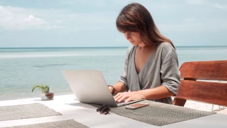 young woman works on laptop in outdoor cafe, moving camera, stabilizer shot