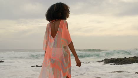 beautiful mixed-race woman raising her arms on the beach