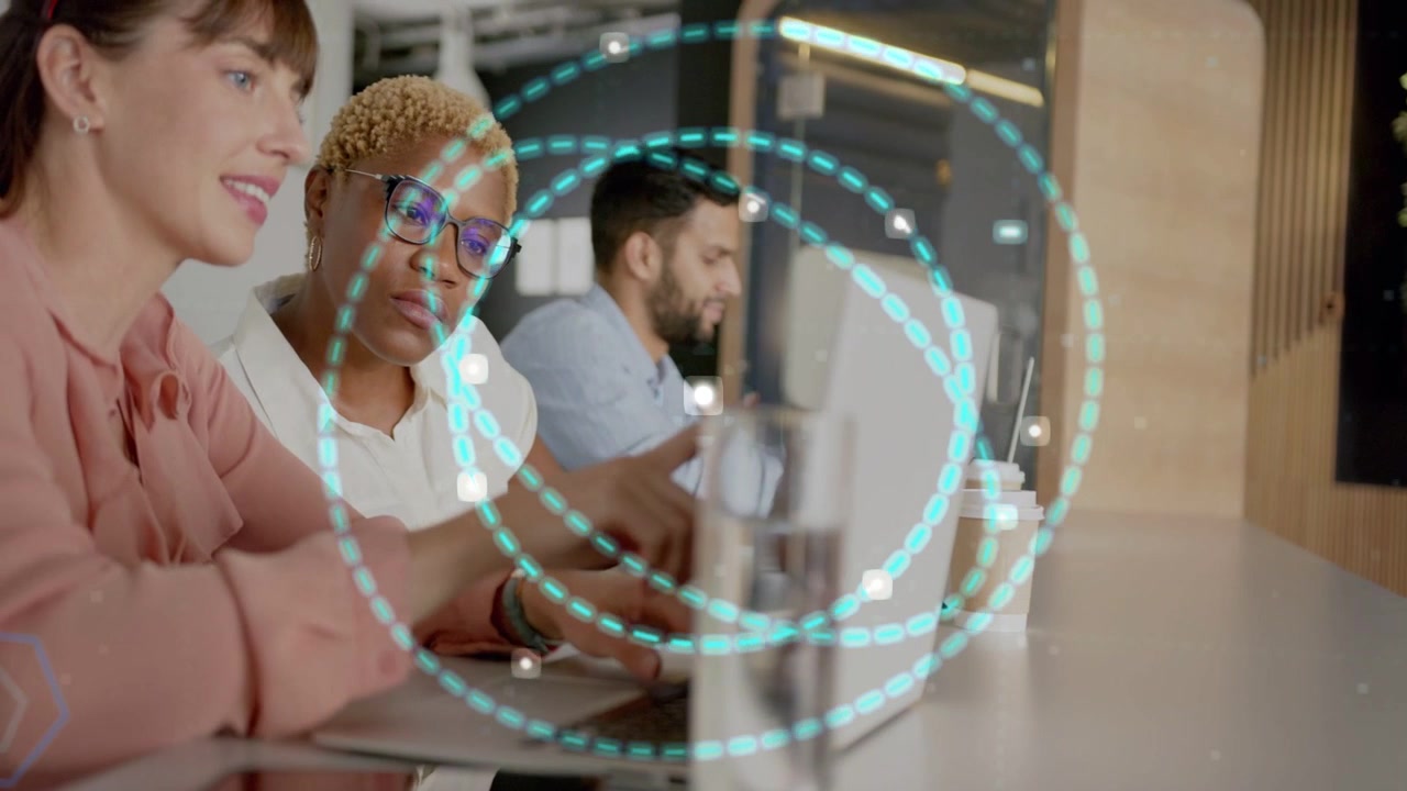 Three at office counter laptops typing teal rings appearing left woman pointing center reviewing