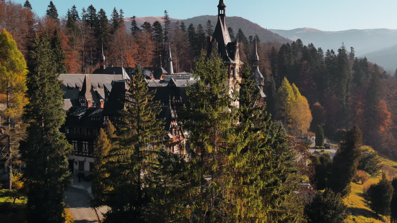 Aerial drone view of The Peles Castle in Romania. Castle with gardens in Carpathians, forest around it. Slow motion