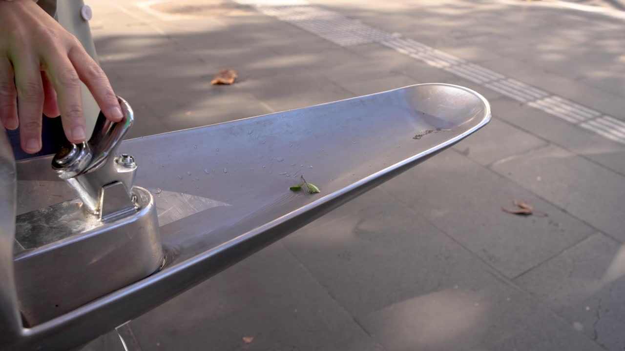 presionando el grifo con la mano para beber agua