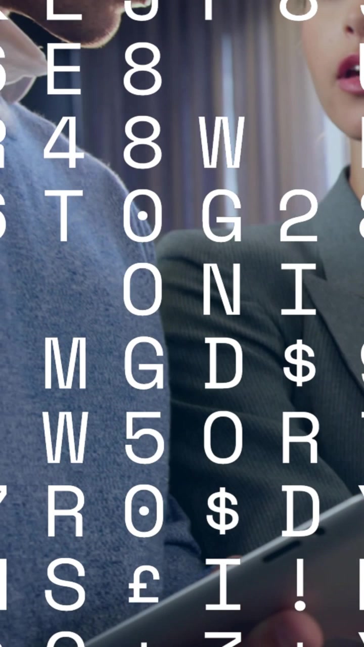 Video verticale: Donna che indica un tablet, uomo che si avvicina, esaminando la tecnologia con una sovrapposizione di codice bianco.