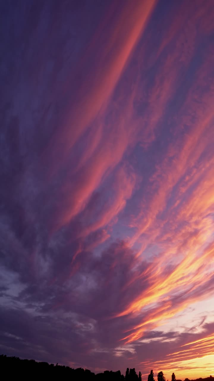 Cielo al tramonto spettacolare con vivaci nuvole rosa e arancioni, catturato da un angolo basso