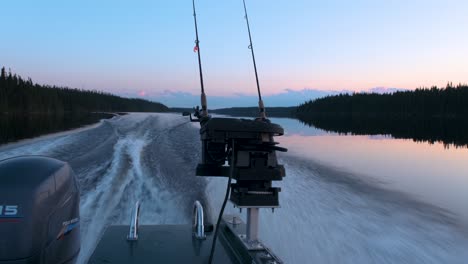 backview of a fishing boat riding at dusk on a calm lake