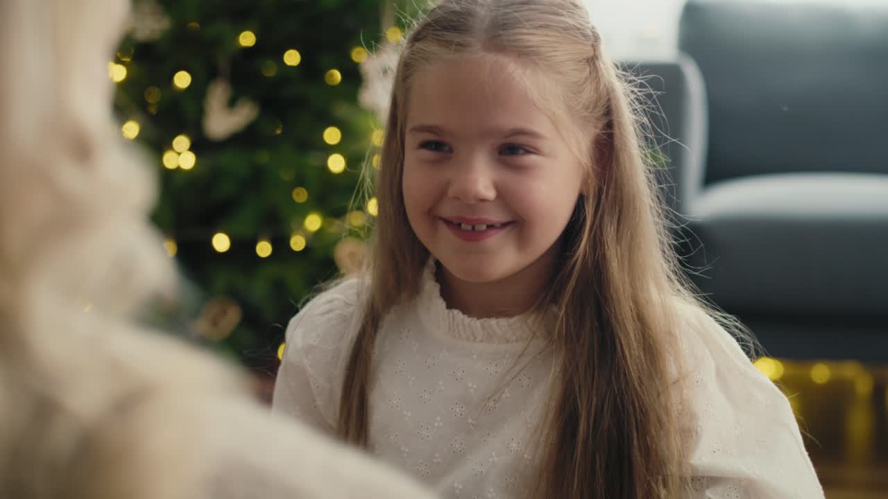 белая девочка обнимает мать после того, как дала и получила рождественский подарок.