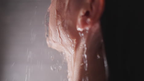 mujer con aerosoles de agua en la cara en la ducha de primer plano. señora tranquila disfruta de procedimientos relajantes en el baño de casa. cuidar el cuerpo y la recreación