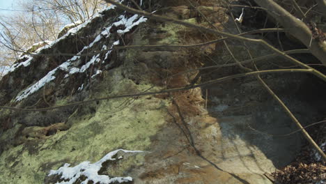 Moving-along-snowy-sandstone-rock-in-Kokorin-Czech-Republic,-close-up