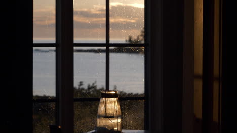 view through nordic hiking cabin window by the sea with sunset sky