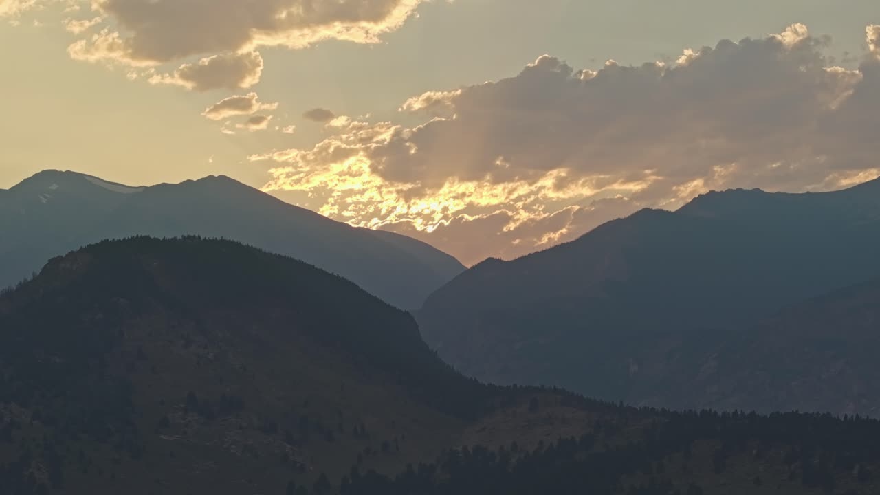 vista aérea de la puesta de sol sobre las montañas, con nubes dramáticas y luz cálida sobre los picos