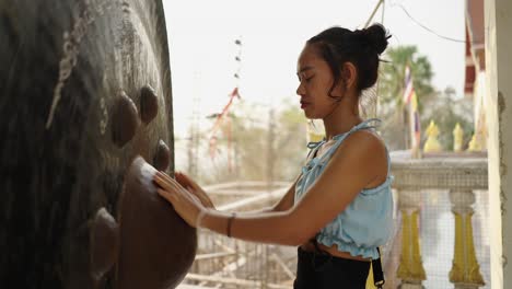 young woman engages in a spiritual ritual at a temple by touching a sacred object