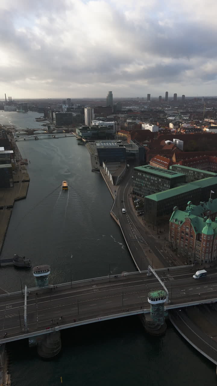 Lodret droneoptagelse, der følger en færge, som sejler i Københavns kanaler ved solnedgang