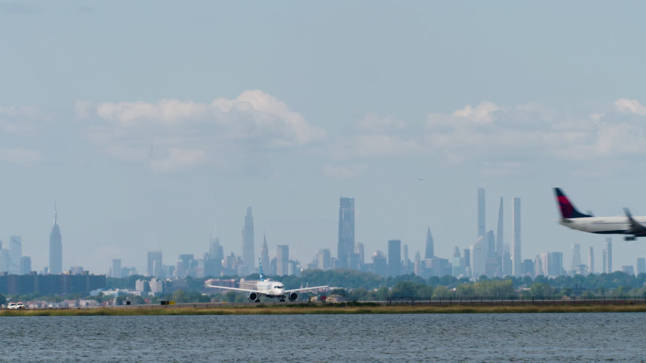 Plane Waits on Runway at JFK Airport in New York City, as Second Plane Crosses Low Overhead Before Landing