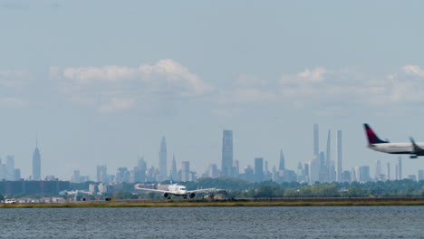 plane waits on runway at jfk airport in new york city, as second plane crosses low overhead before landing