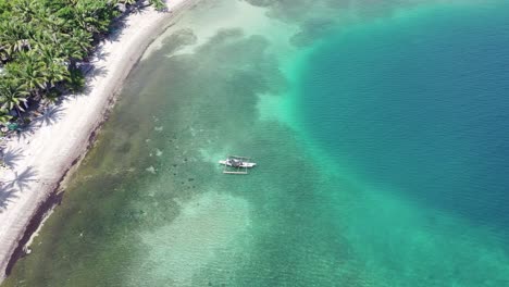 Vista-Aérea-Superior-Sobre-El-Mar-Turquesa-En-Filipinas-Con-Un-Barco-De-Isla-En-Isla-Flotando-Cerca-De-La-Costa-Sobre-Un-Arrecife-De-Coral,-Concepto-De-Viaje