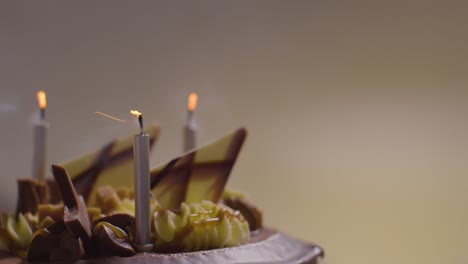 close up studio shot of decorated chocolate birthday celebration cake with lit candles being blown out