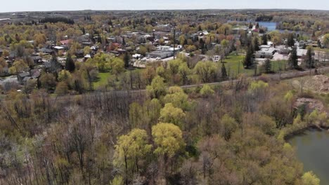 Drone-Volando-Sobre-El-Bosque-Cerca-De-Un-Pequeño-Barrio-De-Acton