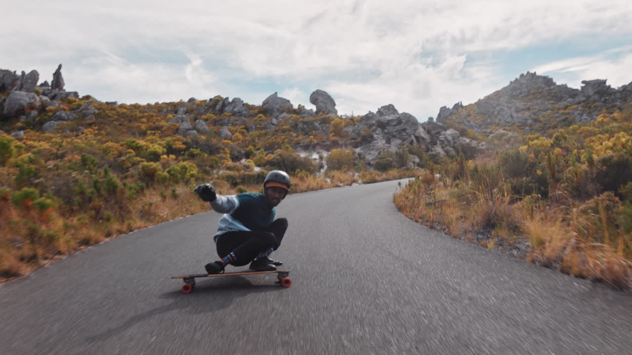 joven afroamericano montando longboard patinaje rápido disfrutando de la navegación cuesta abajo en la carretera del campo haciendo trucos usando skateboard cámara lenta