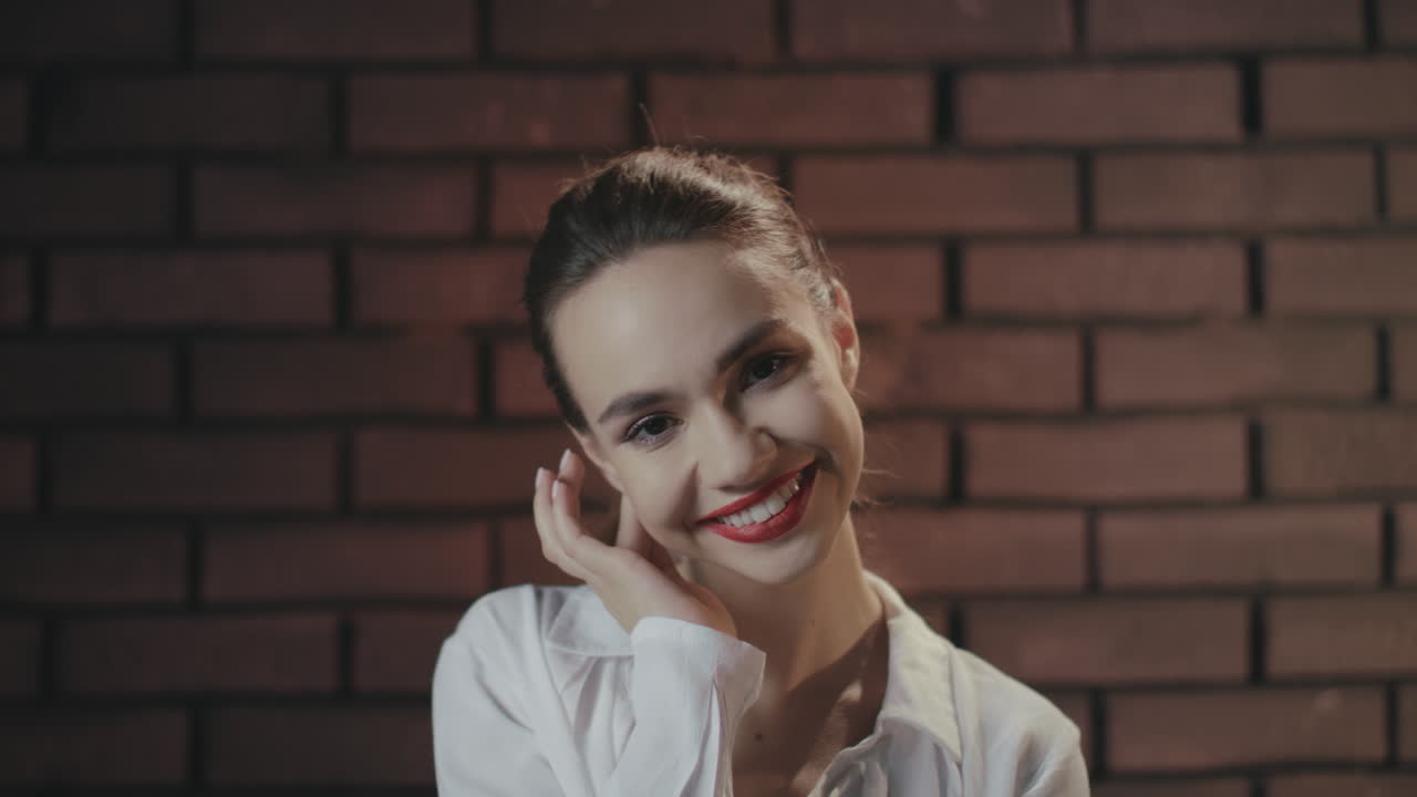 chica elegante tocando el cabello y la oreja mientras posa