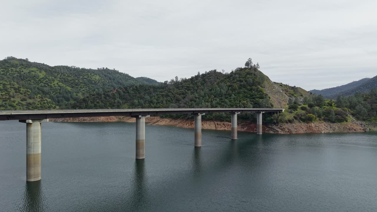 A high-flying drone captures the Don Pedro Reservoir Bridge as it rises above the lake, its reflection dancing on the water. Shot on a DJI Air 3S.