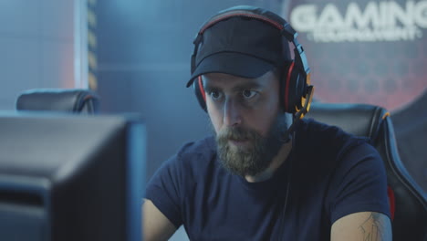 happy young man finishing playing video game and celebrating winning tilt up view of happy caucasian young man finishing playing video game and celebrating winning while sitting in gaming chair in front of computer monitor