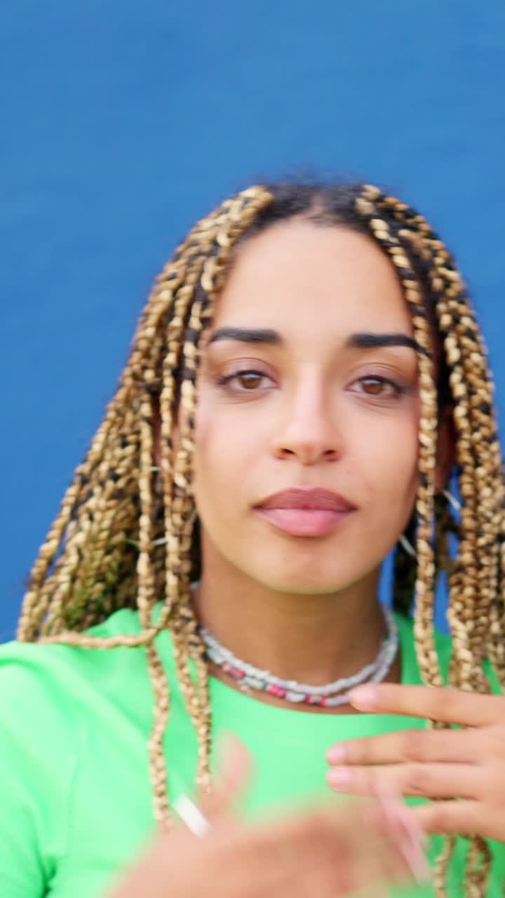 Latin woman smiling at camera next to a blue wall