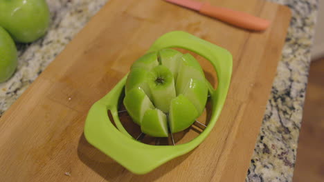 push towards a freshly sliced apple sitting in a slicer on a cutting board in a kitchen