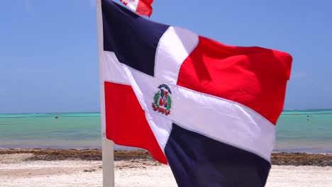 Bandera-De-La-República-Dominicana-Que-Sopla-En-El-Viento-En-La-Soleada-Playa-De-La-Isla-Tropical