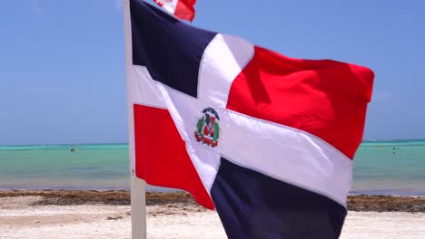 bandera de la república dominicana que sopla en el viento en la soleada playa de la isla tropical