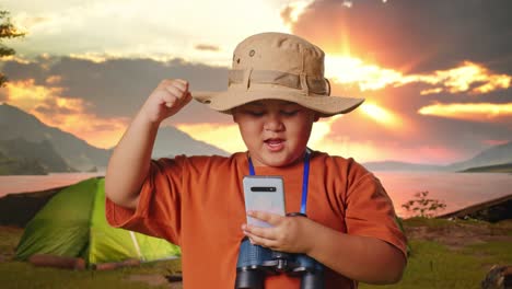 boy camping and exploring with smartphone and binoculars at sunrise/sunset