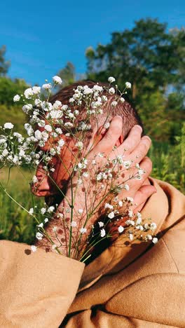 man in a beige coat with flowers in a field