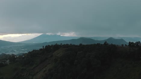 Flying-high-next-to-the-mountains-with-volcanoes-landscape-during-a-cloudy-day-in-Guatemala--Drone-aerial-view